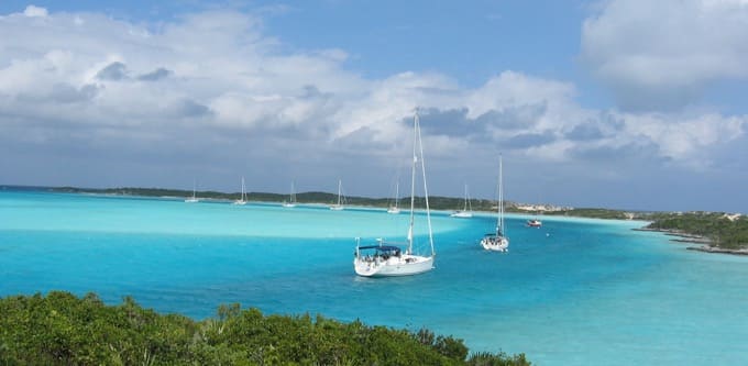 An image of boats docked in the water in the Bahamas. The water is bright blue.