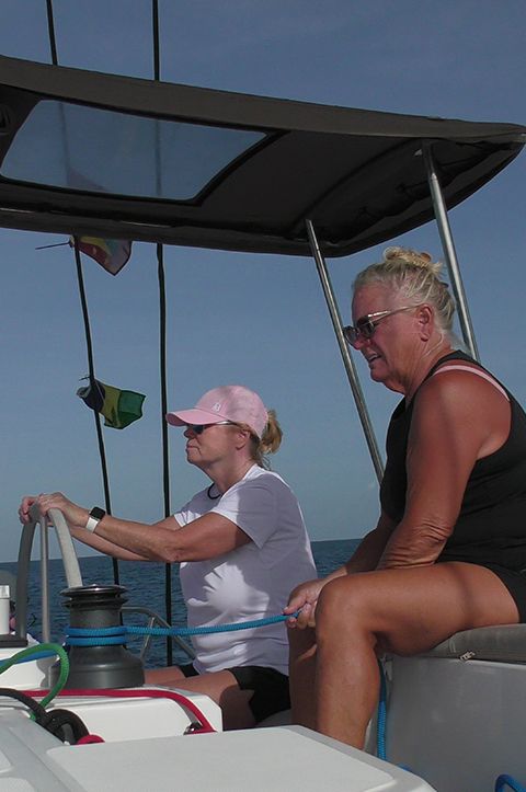 A top-down image of a powerboat being driven along blue seas. There is someone wakeboarding behind the boat.