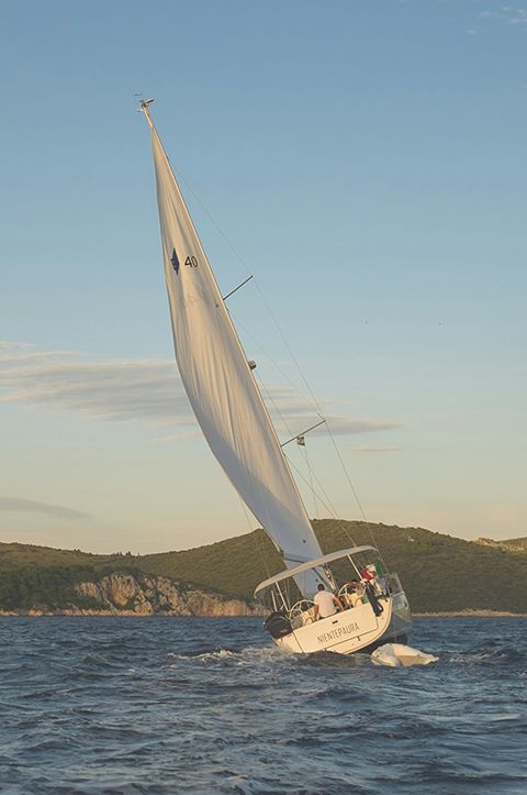 A top-down image of a powerboat being driven along blue seas. There is someone wakeboarding behind the boat.